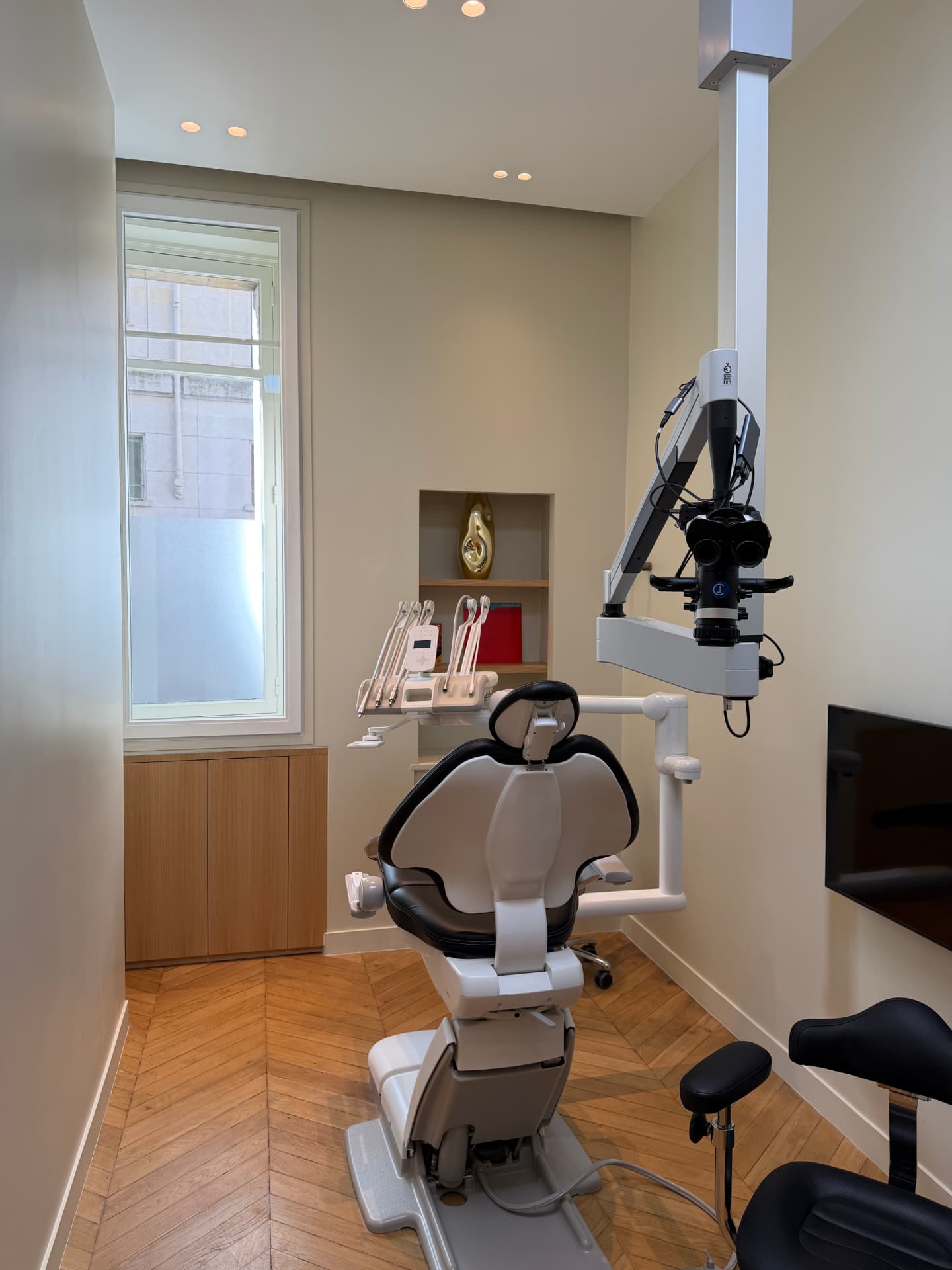 Salle de soins du cabinet : fauteuil et microscope opératoire dédiés à l'endodontie